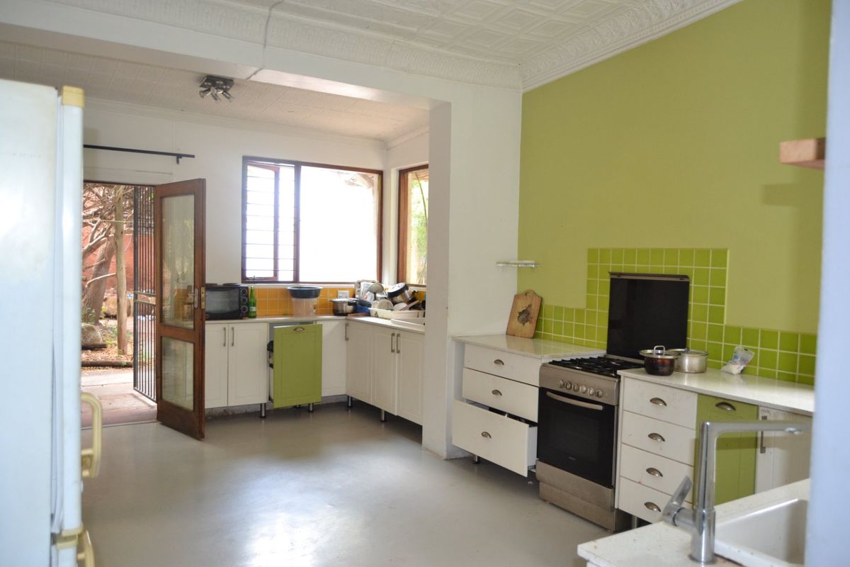 A functional kitchen featuring built-in cabinetry, a tiled splashback, and a freestanding stove, with direct access to an outdoor area.