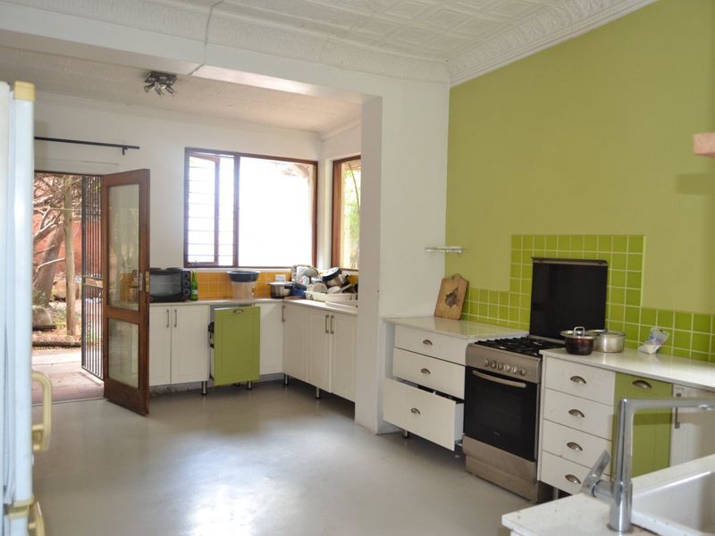 A functional kitchen featuring built-in cabinetry, a tiled splashback, and a freestanding stove, with direct access to an outdoor area.