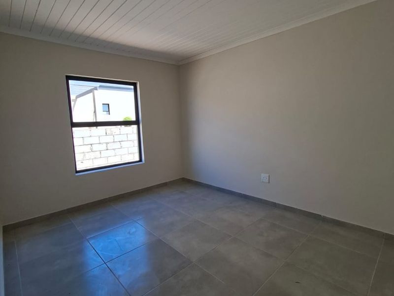 A clean, empty bedroom featuring neutral tiled flooring and a white tongue and groove ceiling, providing a blank canvas for personalization.