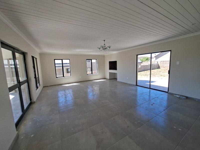 Spacious, empty living area featuring large sliding glass doors, tiled flooring, and a recessed wall niche, offering a bright and versatile open-plan space.