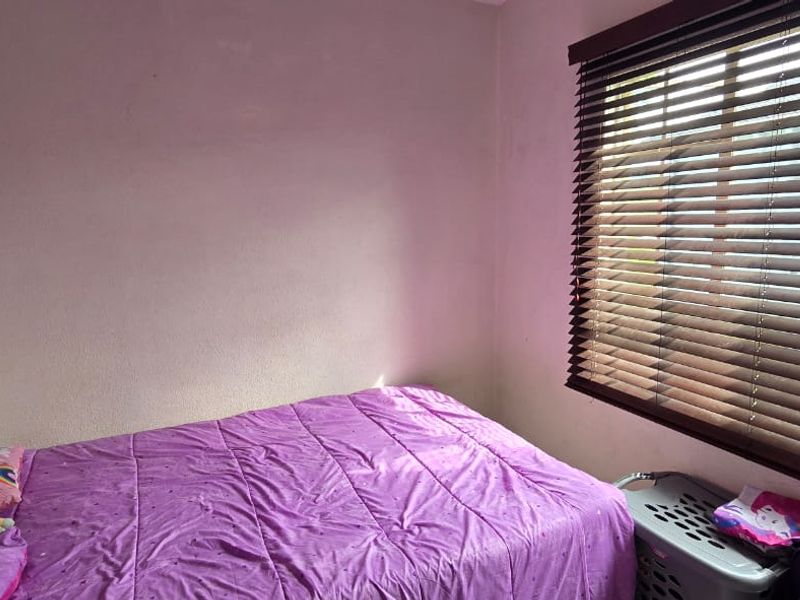 A compact bedroom featuring fitted venetian blinds and plain wall finishes, requiring minor cosmetic updates to improve the overall aesthetic.