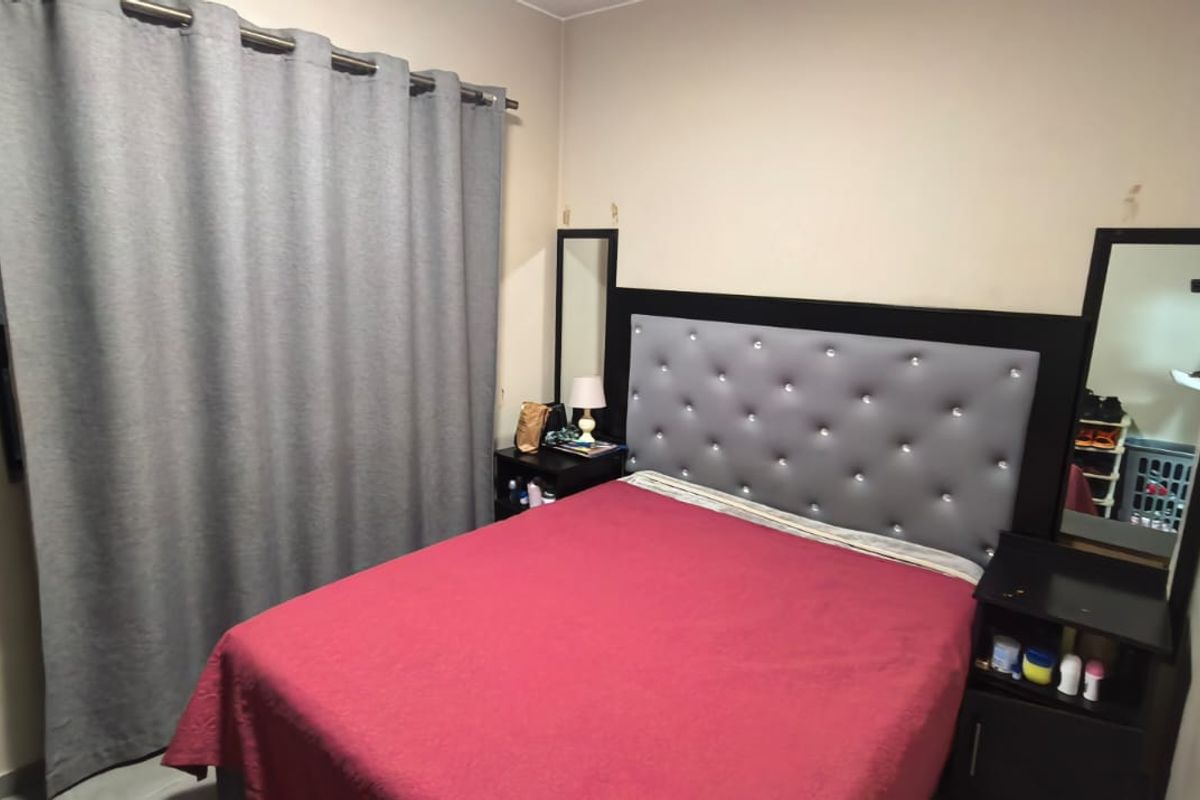A standard bedroom featuring neutral wall tones and a curtained window, providing a functional space for rest.