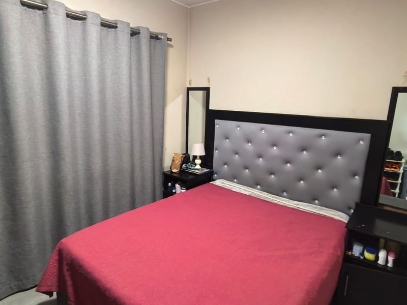 A standard bedroom featuring neutral wall tones and a curtained window, providing a functional space for rest.