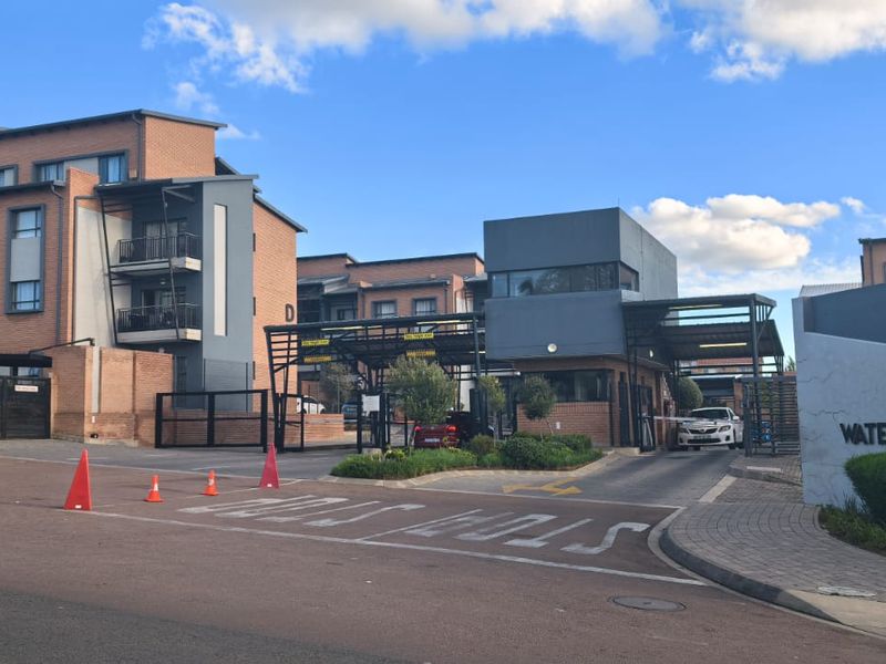 Front entrance and security gate access to the Waterfall Ridge apartment complex, featuring modern brick and render facade architecture.