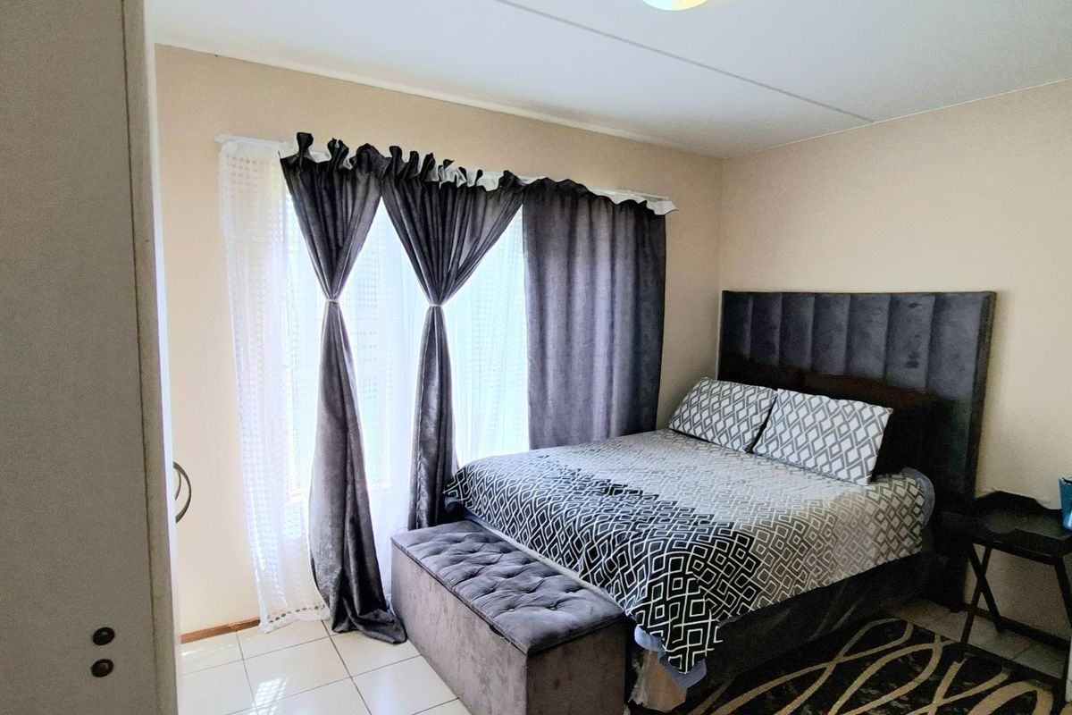 A bedroom featuring tiled flooring and a built-in cupboard, providing a functional living space.