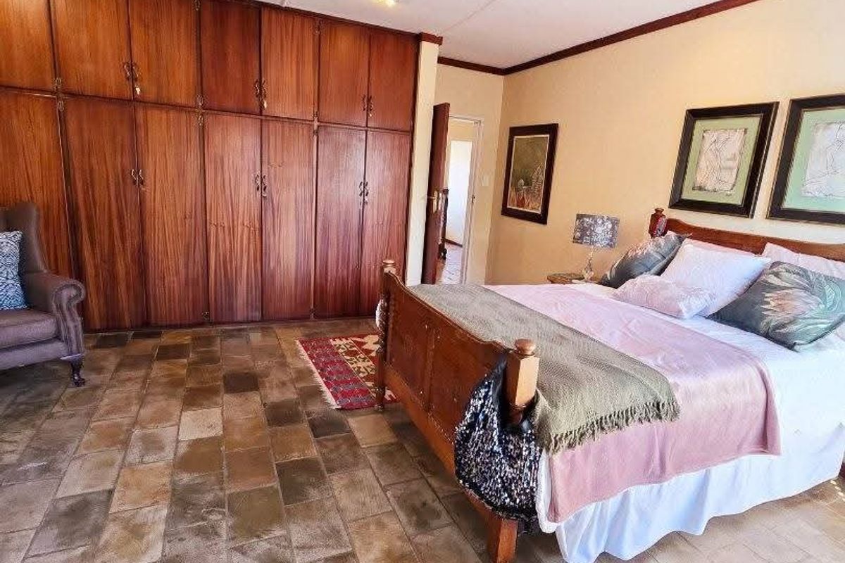 Spacious bedroom featuring extensive built-in wooden cabinetry and durable stone tile flooring, offering a classic aesthetic with ample storage space.