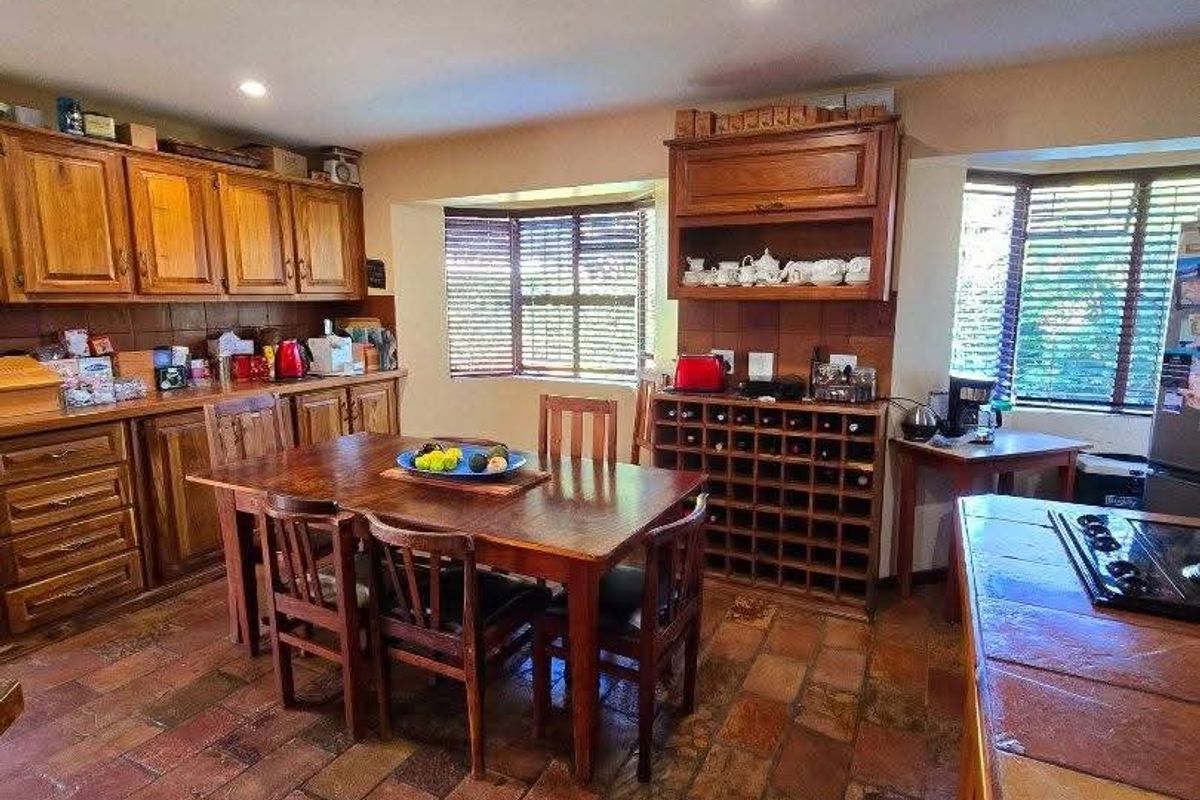 A spacious kitchen featuring traditional wooden cabinetry, stone tile flooring, a built-in wine rack, and large bay windows providing natural light.