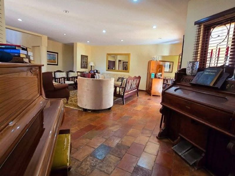 Spacious living area featuring traditional terracotta tile flooring and recessed lighting, offering a warm and inviting atmosphere with ample room for seating arrangements.