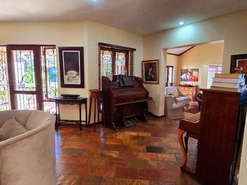 Spacious living area featuring rustic slate tile flooring, recessed lighting, and large timber-framed windows providing natural light and access to the exterior.