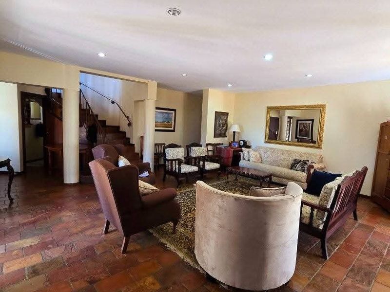 Spacious living room featuring rustic stone tile flooring, recessed lighting, and an open-plan layout with a staircase leading to the upper level.