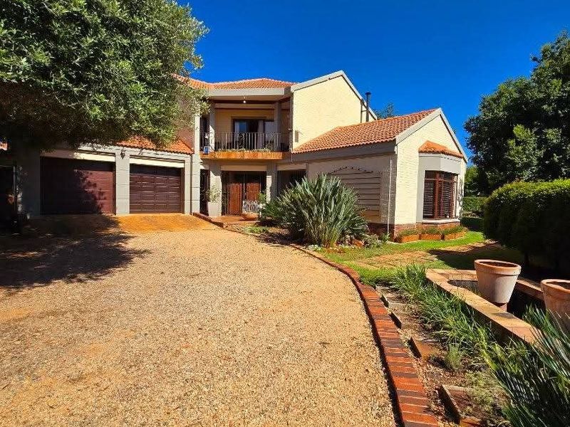 Front elevation of a two-story house featuring a gravel driveway, double garage, and an upper-level balcony with terracotta roof tiles.