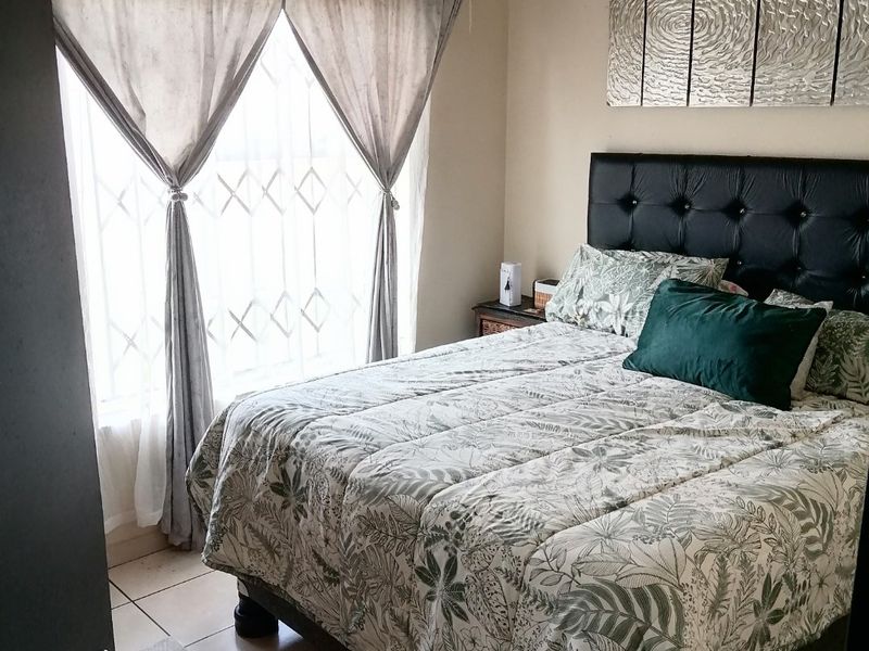 A functional bedroom featuring tiled flooring and a window fitted with a security gate, providing a practical and secure sleeping space.
