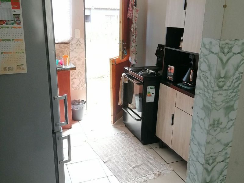 A functional kitchen featuring built-in cabinetry, tiled flooring, and direct access to the exterior through a rear door.