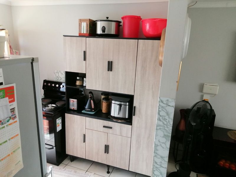 A kitchen area featuring a freestanding stove and modern wood-look cabinetry providing ample storage space.