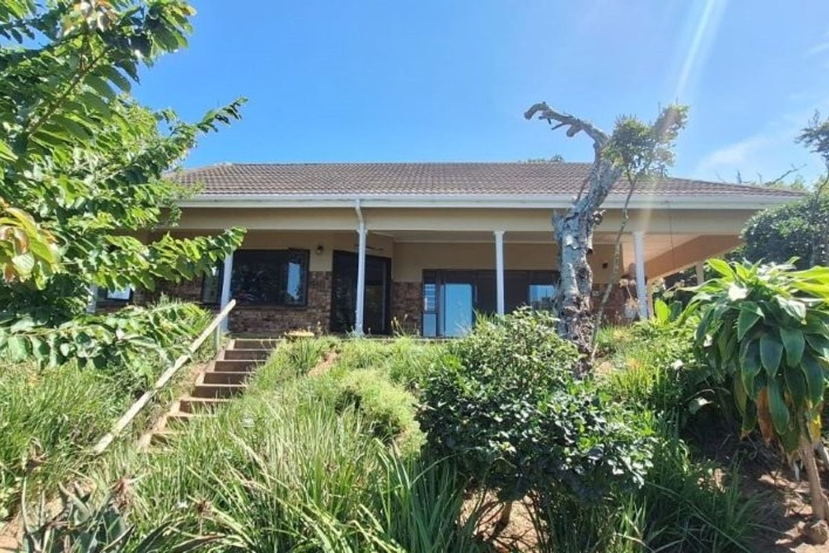 Rear view of the house featuring a covered patio, brick facade, and concrete stairs leading up from the garden.