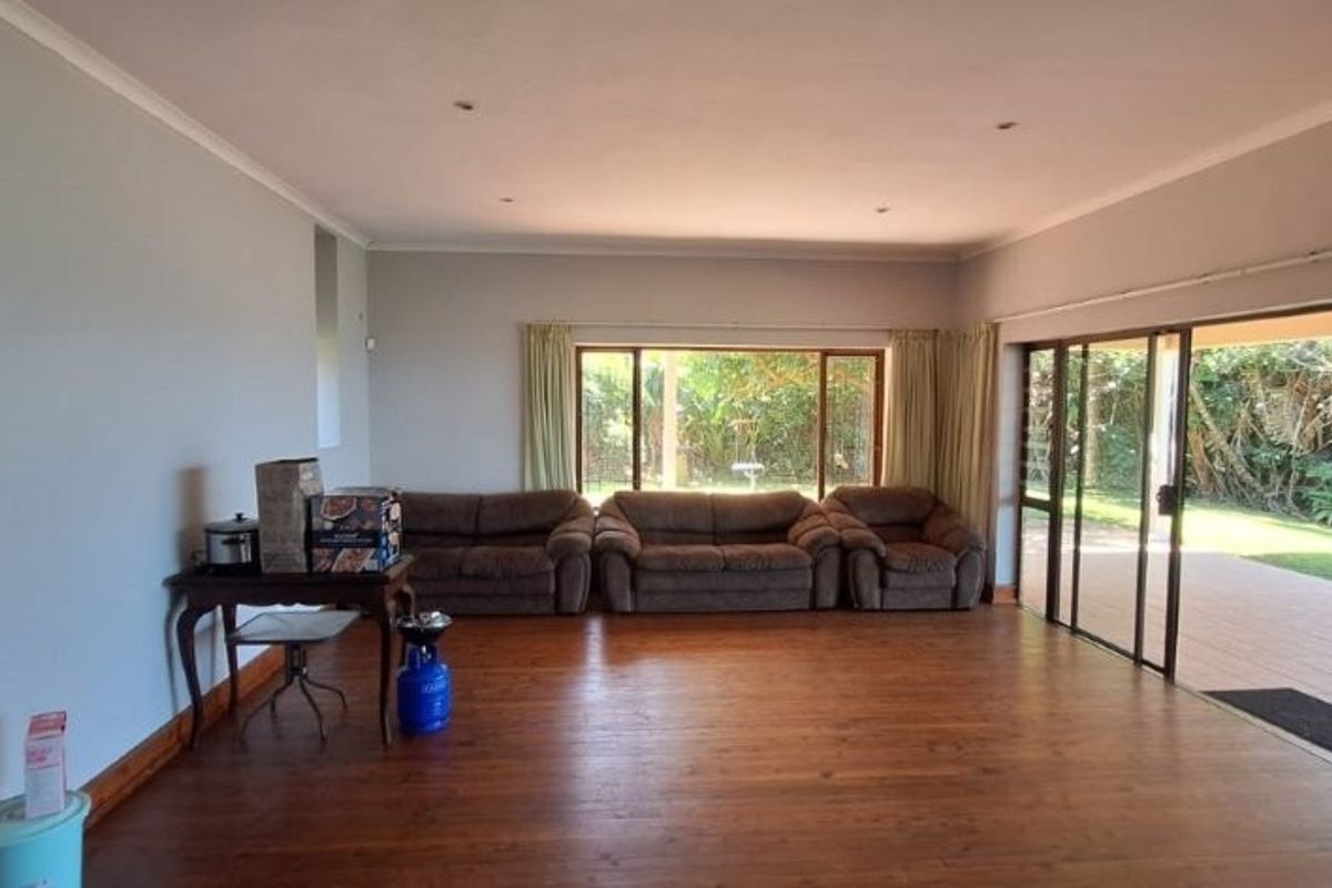 Spacious living room featuring polished hardwood flooring, recessed lighting, and large sliding glass doors providing seamless access to the outdoor patio area.