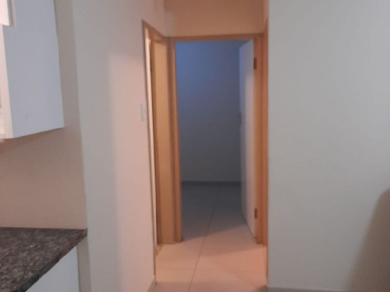 A neutral hallway featuring tiled flooring and clean finishes, providing access to adjacent rooms within the property.