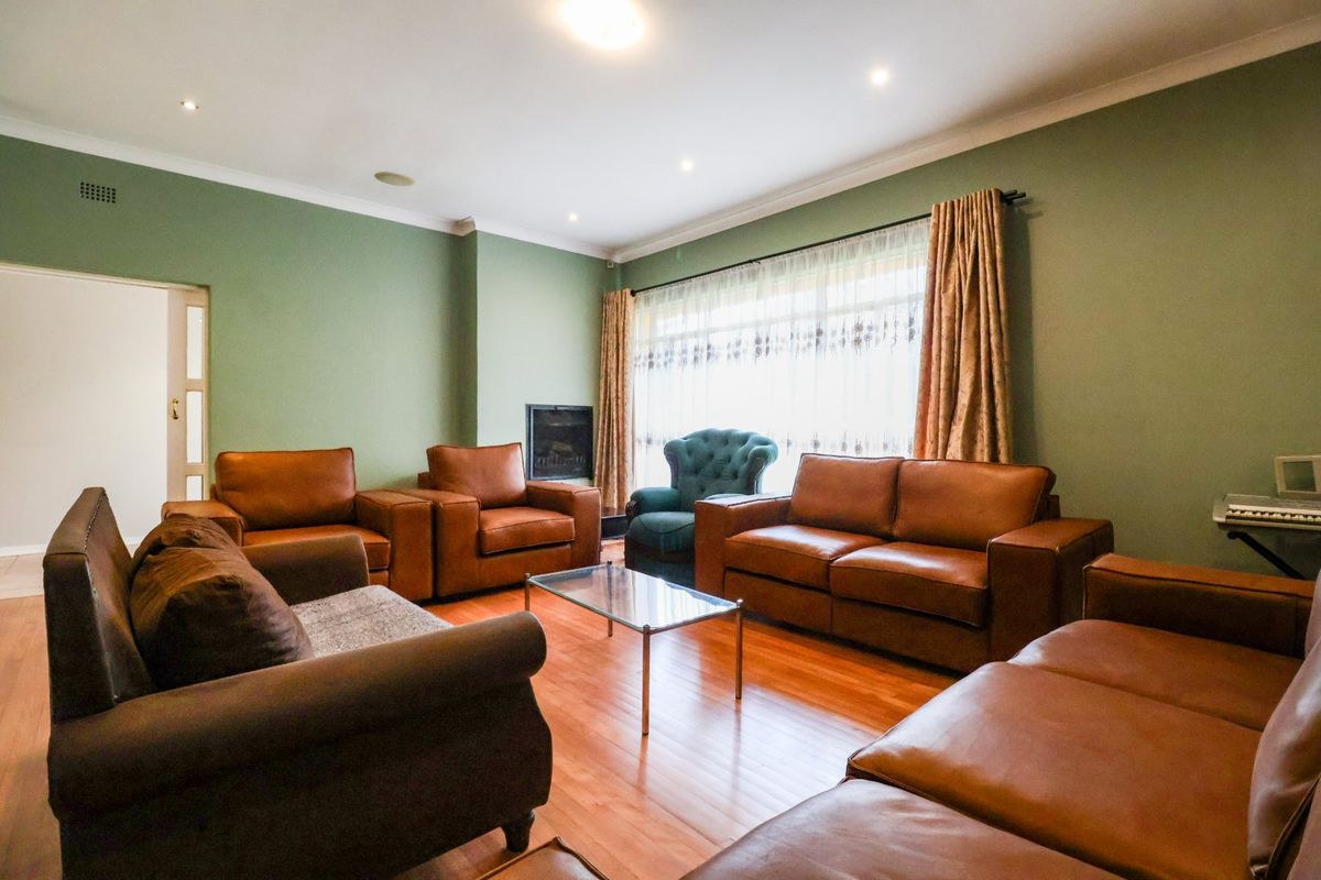 A spacious living room featuring warm timber flooring, recessed downlighting, and a built-in fireplace, creating a comfortable and inviting atmosphere.