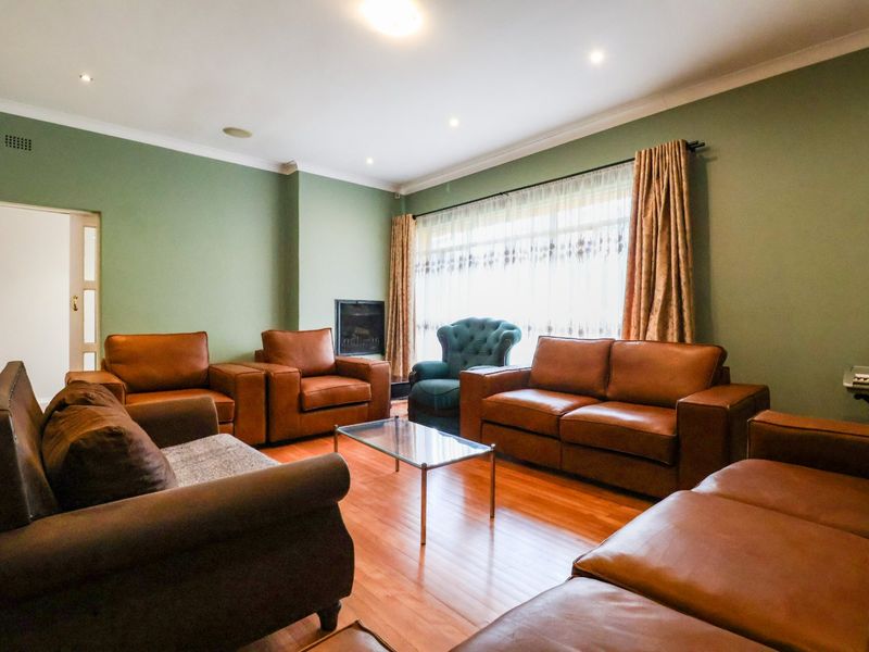 A spacious living room featuring warm timber flooring, recessed downlighting, and a built-in fireplace, creating a comfortable and inviting atmosphere.