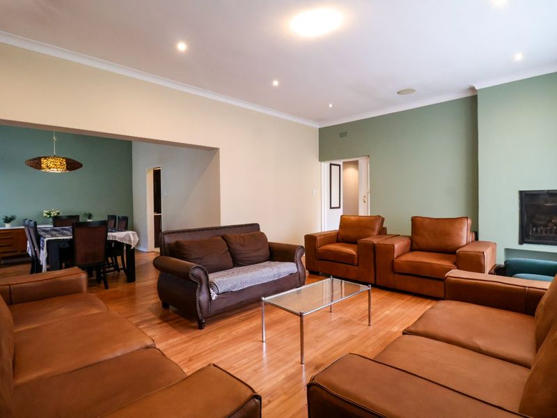 Spacious open-plan living and dining area featuring hardwood flooring, recessed lighting, and a built-in fireplace, offering a versatile layout for family living.