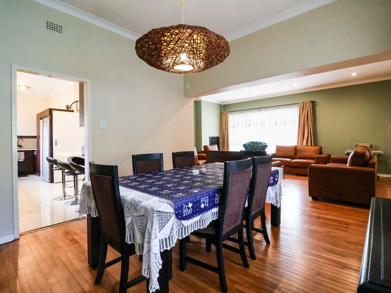 Spacious open-plan living and dining area featuring warm hardwood flooring, neutral wall tones, and a seamless transition into the adjacent kitchen space.