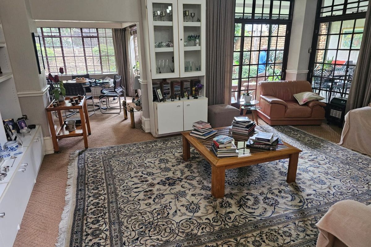 Spacious living room featuring large multi-pane glass doors, built-in cabinetry, and carpeted flooring, offering a bright and traditional living space.