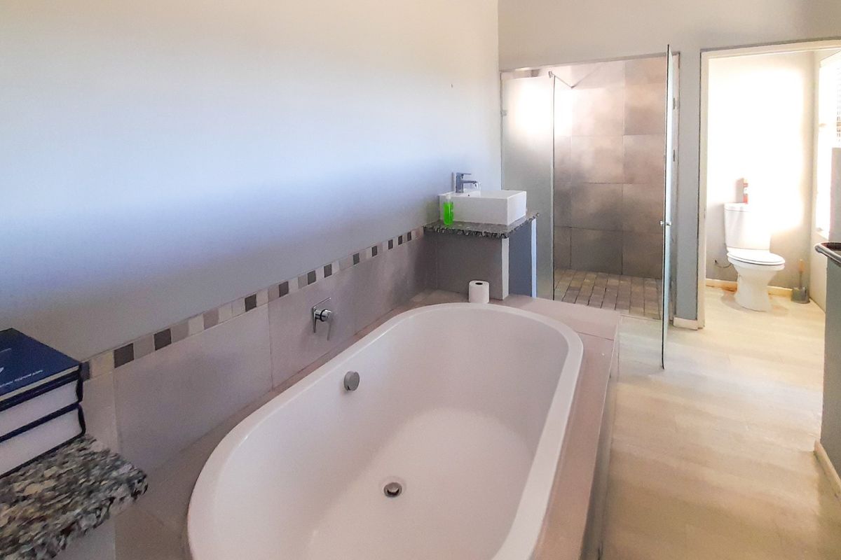 A spacious bathroom featuring a built-in bathtub, granite-topped vanity with vessel sink, and a separate glass-enclosed shower area.