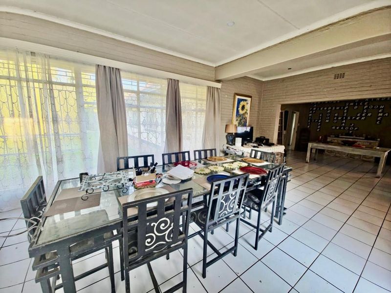 Spacious dining area featuring large windows, tiled flooring, and an exposed brick feature wall, offering a bright and open layout.