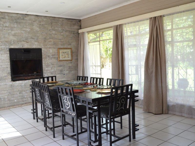 Spacious dining room featuring an exposed brick wall with a built-in fireplace, tiled flooring, and large windows providing natural light.