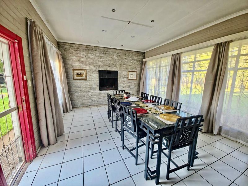 Spacious dining room featuring a built-in fireplace, exposed brick wall, and large windows providing ample natural light.