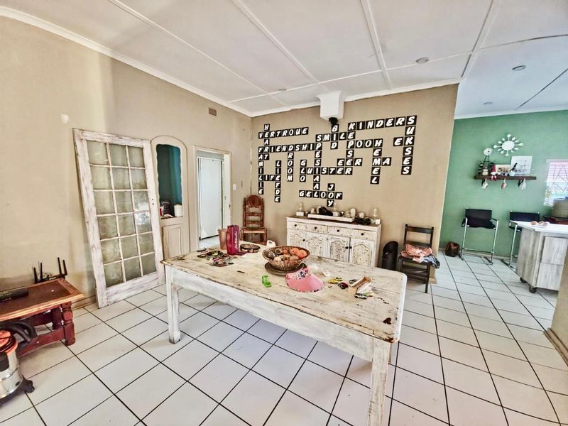 Open plan living area featuring tiled flooring and a panelled ceiling, offering a versatile space for dining or casual living.