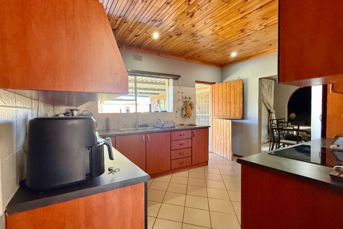 A functional kitchen featuring wooden ceiling panels, tiled flooring, built-in cabinetry, and a convenient dutch door leading to the exterior.