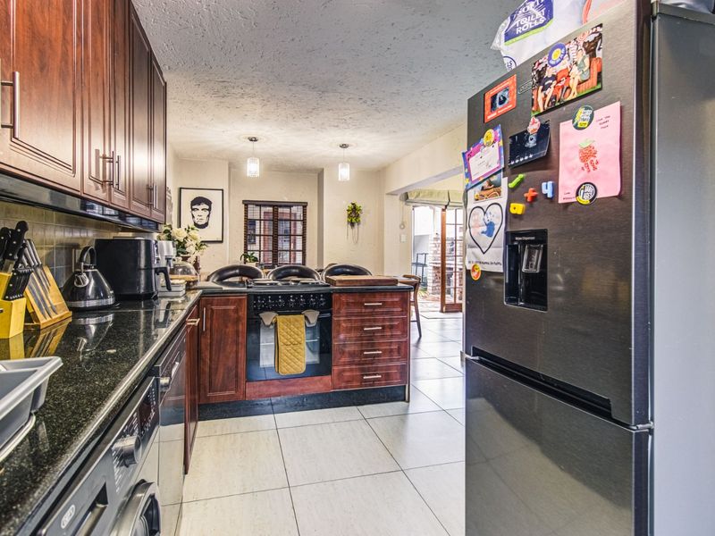 A functional kitchen featuring dark wood cabinetry, granite countertops, and a built-in oven, flowing into an open-plan living area.