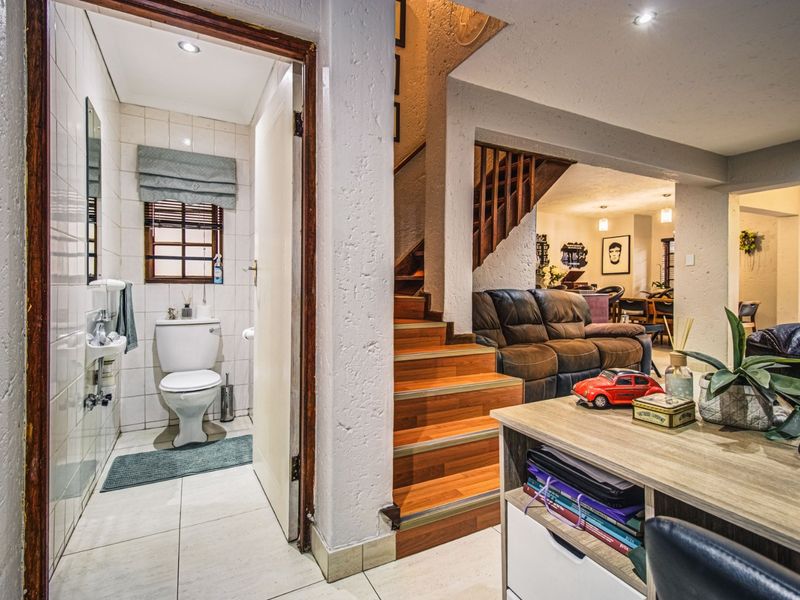Open plan living area featuring a wooden staircase and an adjacent guest bathroom with tiled finishes and modern fixtures.