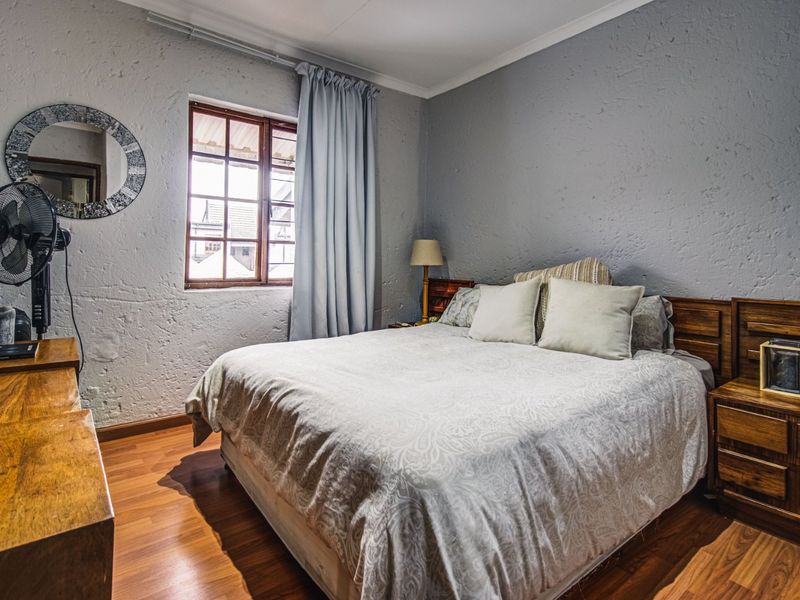 A cozy bedroom featuring textured walls, laminate flooring, and a timber-framed window, offering a comfortable and functional living space.
