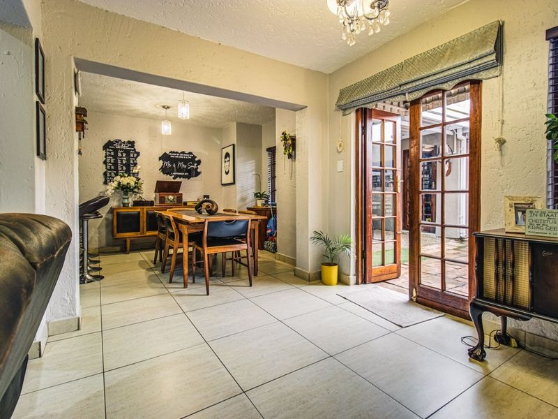 Open plan living and dining area featuring tiled flooring and wooden French doors providing direct access to the outdoor patio area.