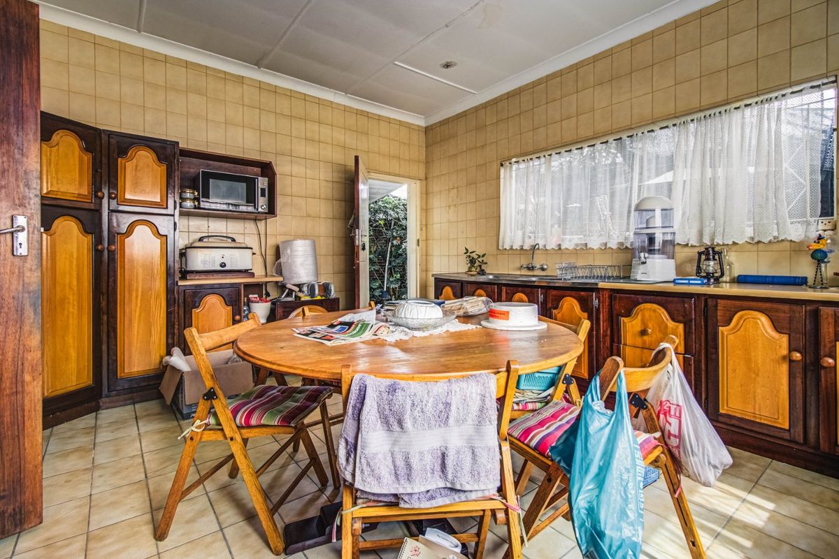 A dated kitchen featuring traditional wooden cabinetry, tiled walls, and tiled flooring, offering significant potential for a modern renovation.