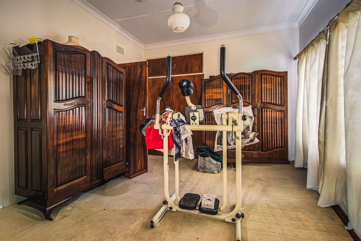 A bedroom featuring built-in wooden cupboards and carpeted flooring, requiring cosmetic updates to modernize the space.