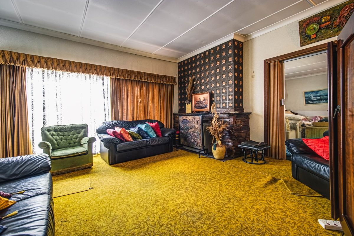 Spacious living room featuring a prominent decorative fireplace and large windows, offering a classic layout with potential for modern updates.