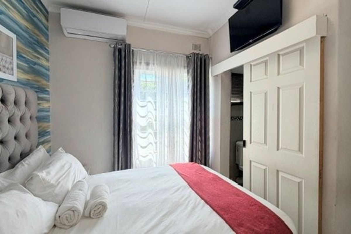 A bedroom featuring a split-system air conditioner, sliding door access to an en-suite, and decorative wall finishes.