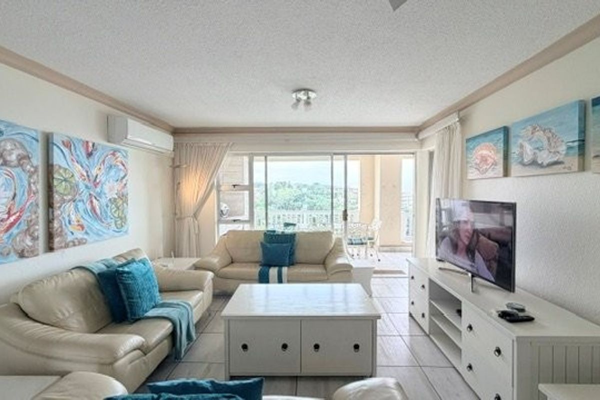 A comfortable living room featuring tiled flooring, a split-system air conditioner, and large sliding glass doors that open onto a balcony.