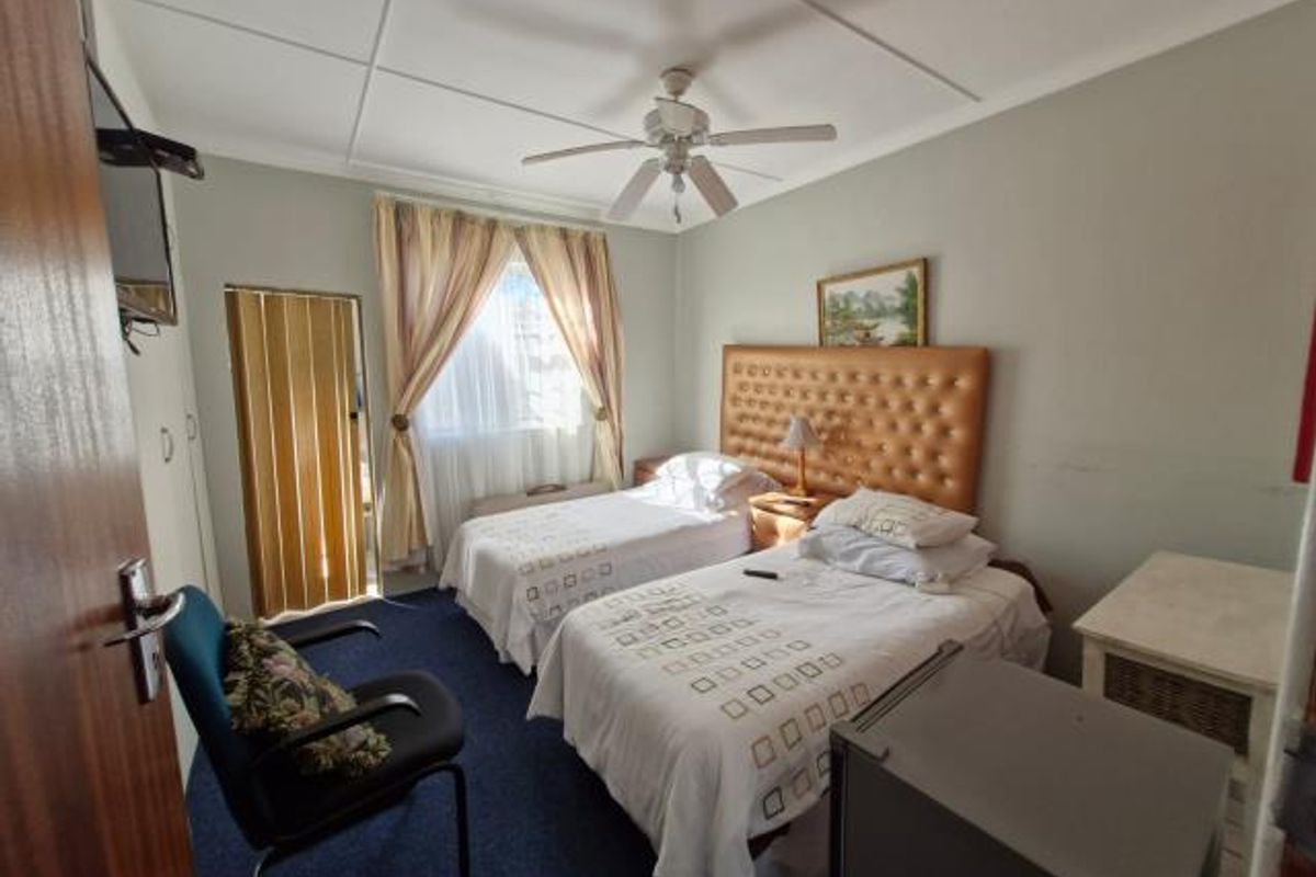 A functional bedroom featuring a ceiling fan, built-in cupboards, and a folding door leading to an adjacent space.