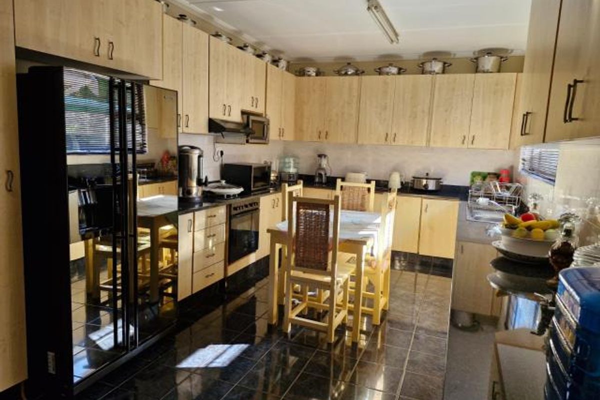 A functional kitchen featuring light wood-look cabinetry, dark granite countertops, and dark tiled flooring, providing ample storage and workspace.