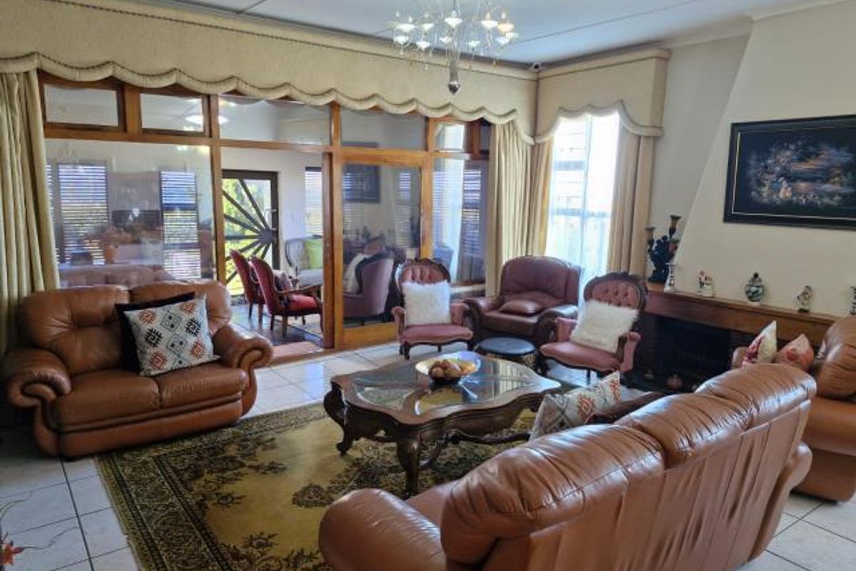 Spacious living room featuring a built-in fireplace, tiled flooring, and large glass sliding doors providing access to an enclosed patio area.