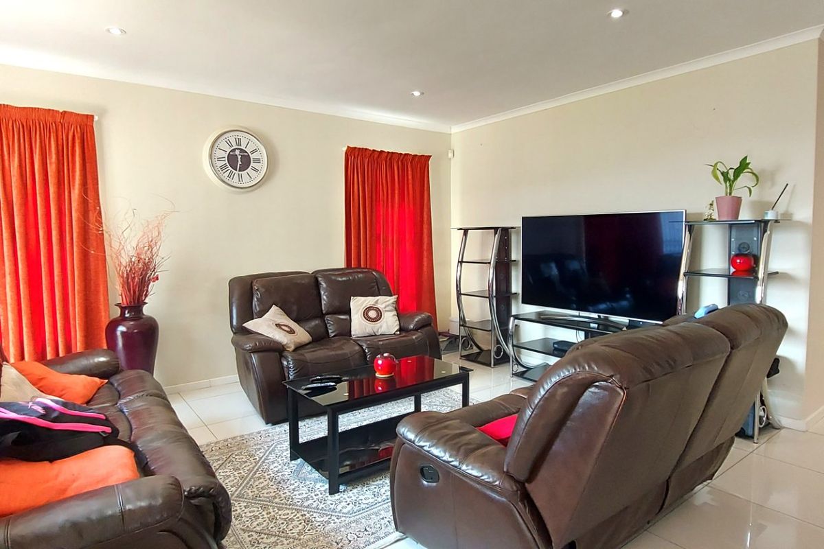 A spacious living room featuring tiled flooring, recessed downlighting, and coved cornicing, providing a neutral and functional base for comfortable family living.