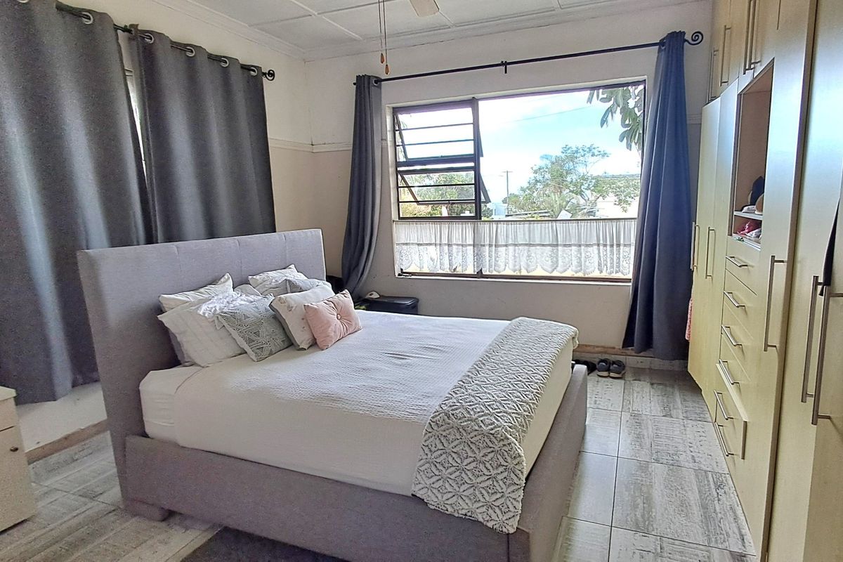 A bedroom featuring built-in cupboards, tiled flooring, and a large window providing natural light.