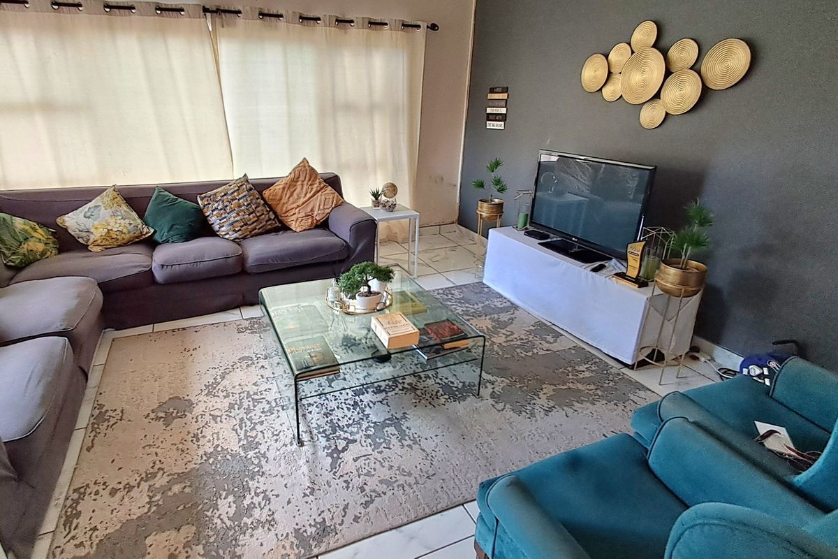 A living room featuring tiled flooring and a dark accent wall, providing a functional space for relaxation.