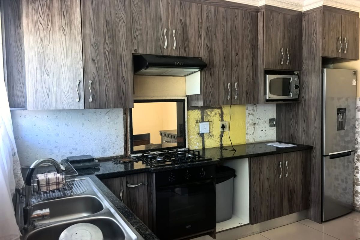 Kitchen featuring wood-grain cabinetry, granite countertops, built-in oven, and hob, currently requiring backsplash completion and minor finishing touches.