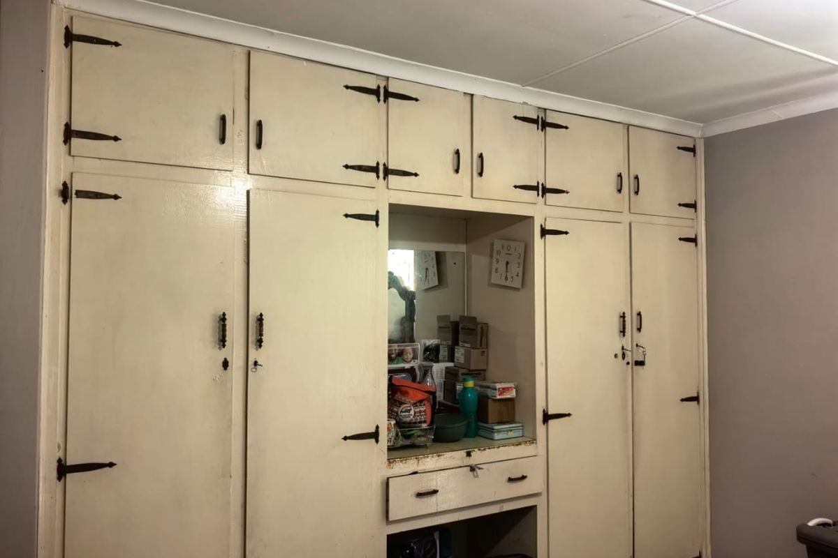 A bedroom featuring floor-to-ceiling built-in wooden cabinetry with integrated storage and a central vanity area.