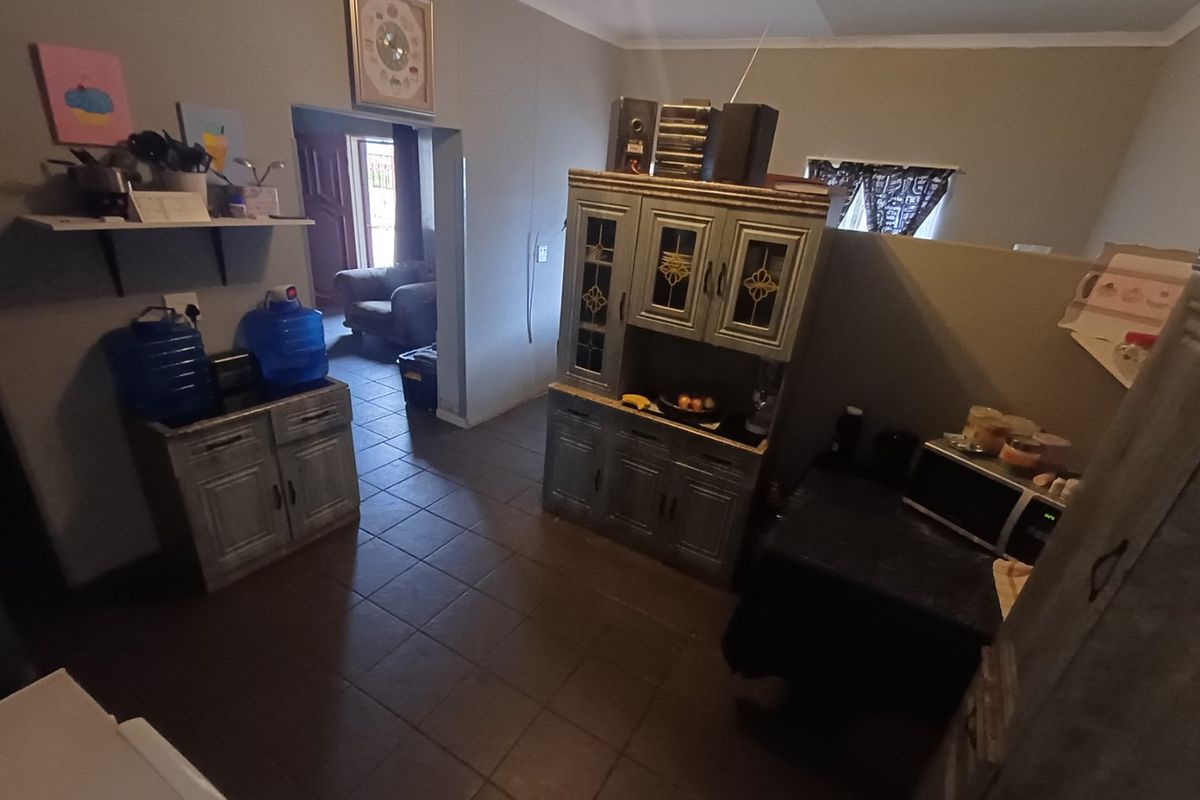 A functional kitchen area featuring tiled flooring and built-in cabinetry, providing a practical layout with direct access to the adjacent living space.